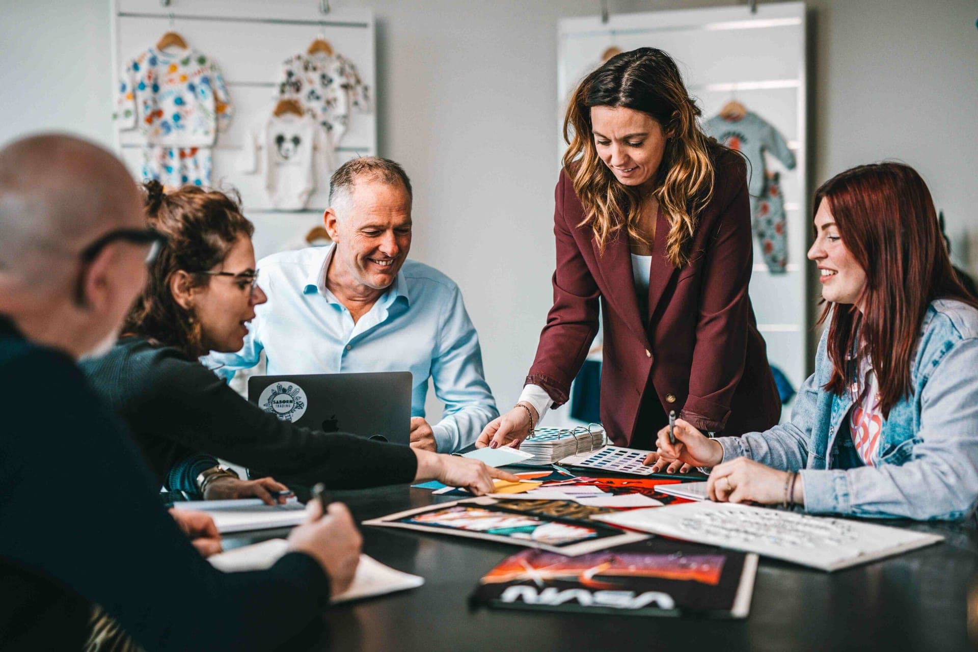 Team bespricht Farben und Designs an einem Tisch mit Stoffmustern und Artwork von Lizenzgebern