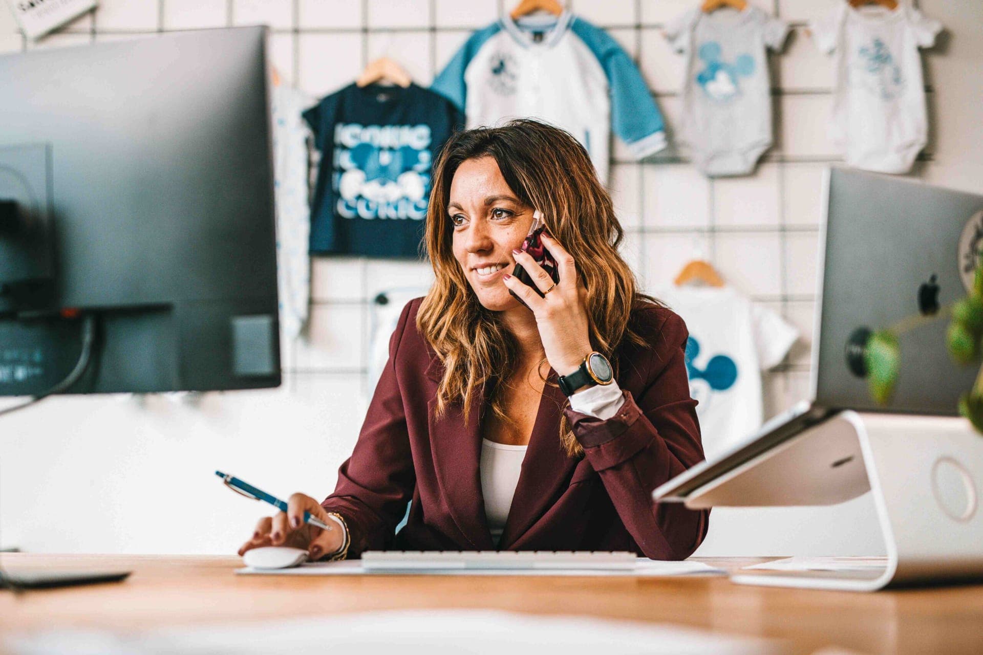 Colleague on the phone at her desk, with licensed Mickey Mouse children's clothing hanging on the wall behind her
