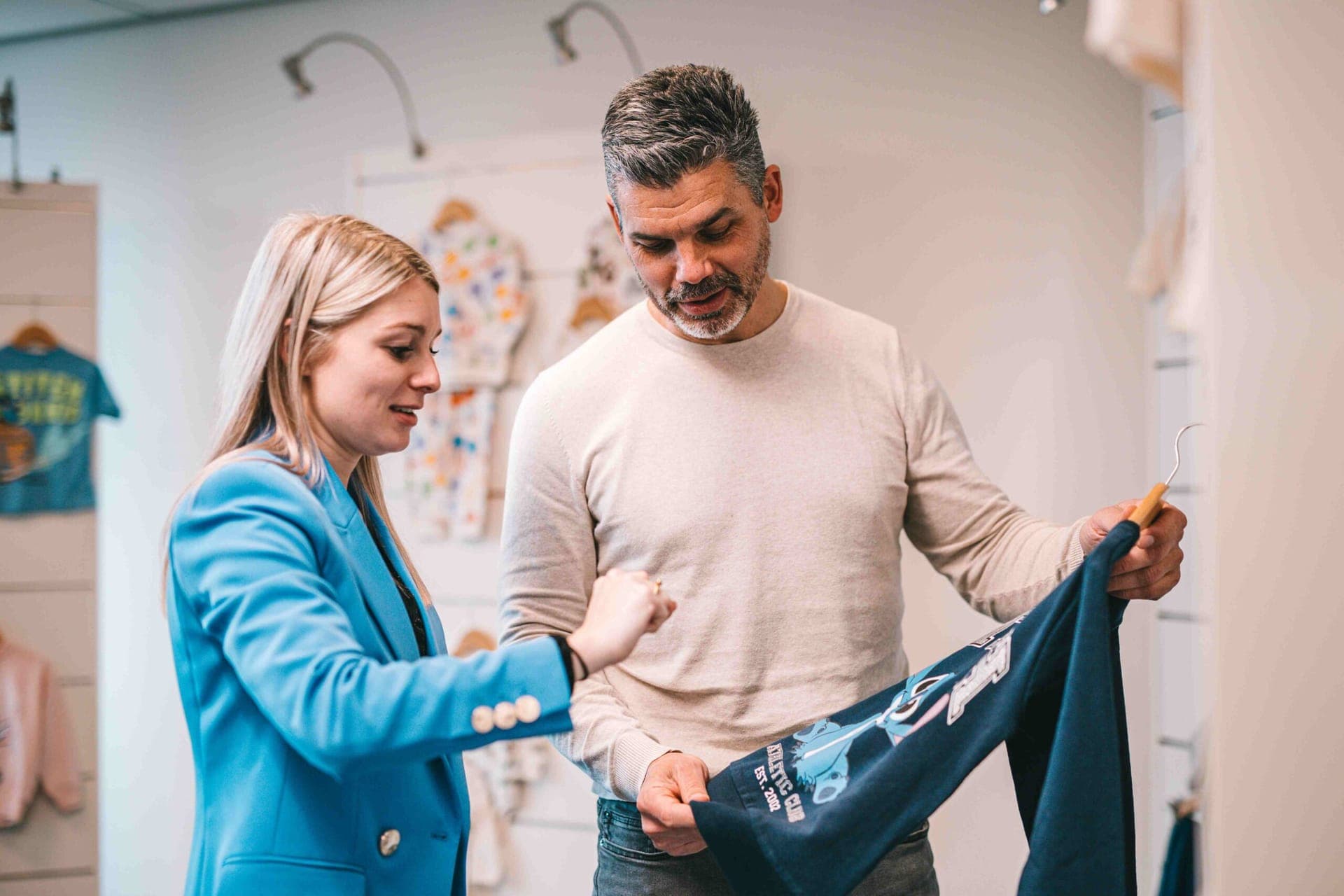 Two colleagues inspecting a navy Stitch sweatshirt in the showroom