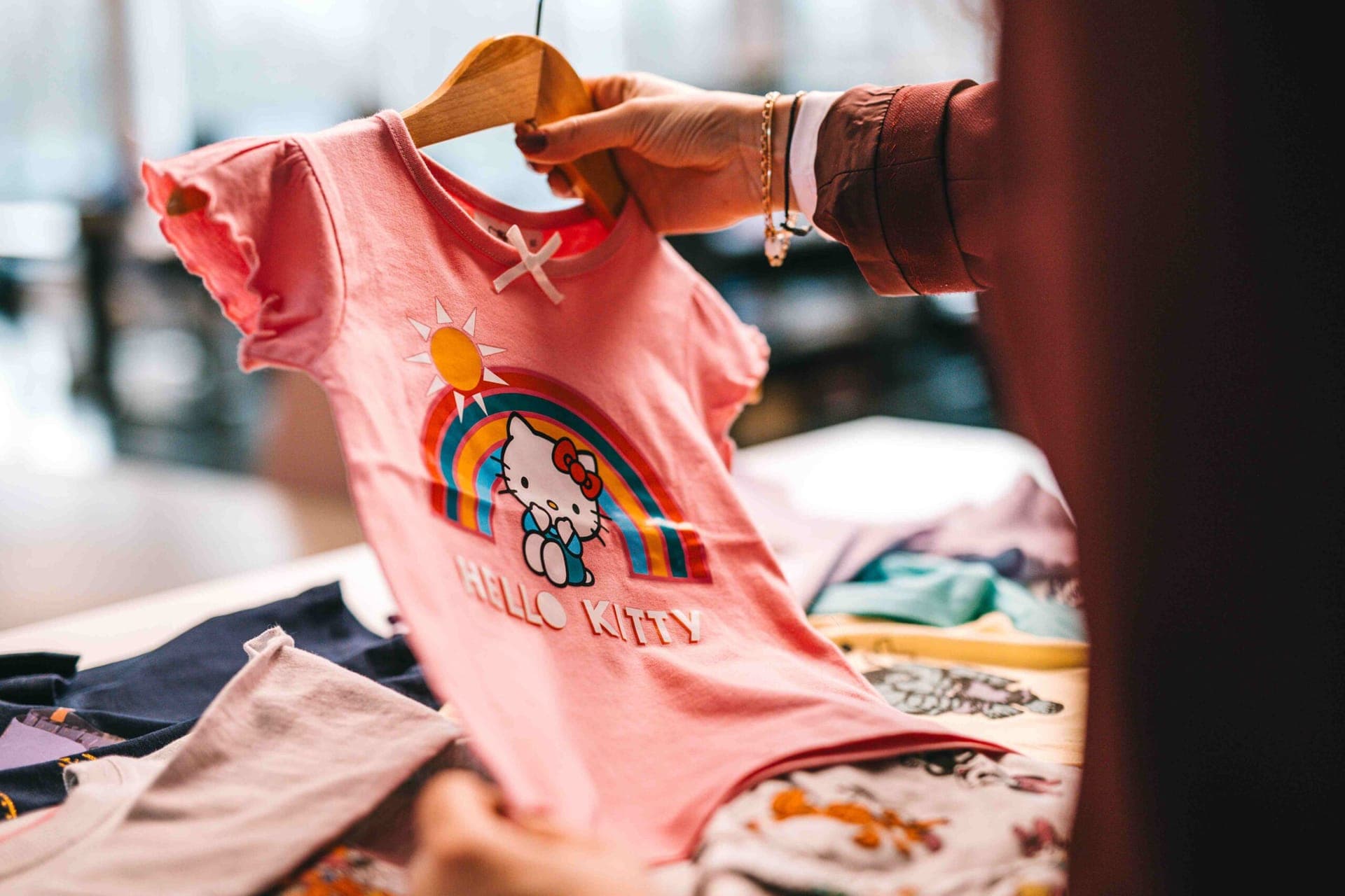 T-shirt rose Hello Kitty avec un arc-en-ciel imprimé sur un cintre